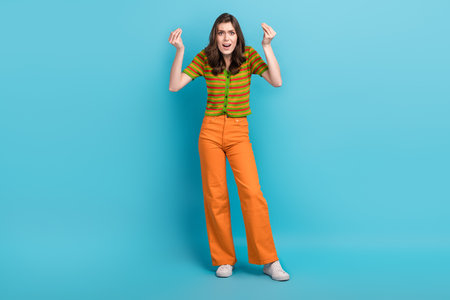 Photo of aggressive crazy girl with curly hairstyle wear striped shirt conflicting quarrels fingers up isolated on blue color backgroundの写真素材