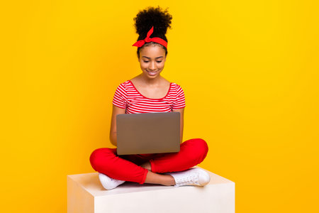 Full size photo of funky young girl work netbook sit white podium wear trendy red striped clothes isolated on yellow color backgroundの写真素材