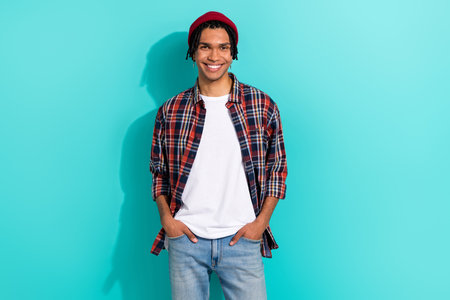 Photo portrait of attractive young guy hands pockets jeans model dressed stylish checkered garment isolated on cyan color backgroundの写真素材