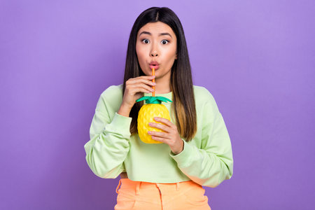Photo of astonished impressed pretty woman dressed green shirt drink tasty beverage from ananas cup...