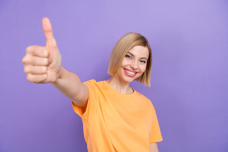 Portrait of young girl raise thumb finger up approve nice good quality novelty product put like isolated purple color backgroundの写真素材
