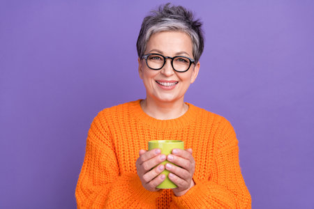 Closeup portrait of friendly model senior woman grey short hair hold green mug coffee break...