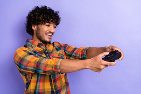Photo of young guy arab wear trendy stylish shirt holding wireless gamepad addicted playing isolated...