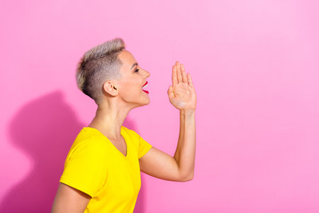 Profile photo of funky positive girl hand near mouth communicate talk empty space isolated on pink color backgroundの写真素材