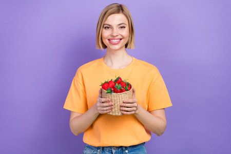 Portrait of cheerful attractive young girl hold basket vitamins red sweet strawberries summer dessert isolated on violet color backgroundの写真素材