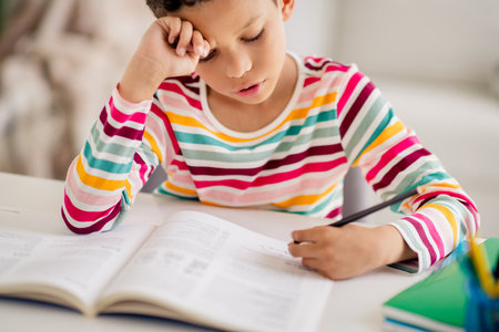 Closeup photo of childhood diligent young small boy writing copybook planner calculate mathematics isolated over apartment backgroundの写真素材