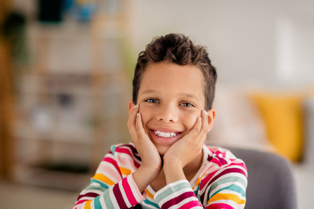 Closeup portrait of small young schoolboy touch cheeks spend time playroom every weekend having fun isolated indoors home backgroundの写真素材