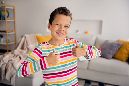 Closeup photo of young small school boy double thumbs up positive good mood enjoy spend time playroom isolated on blurred backgroundの写真素材