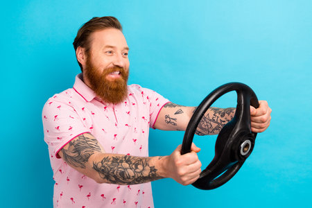 Photo of satisfied man with redhair beard wear pink t-shirt hold steering wheel look empty space...
