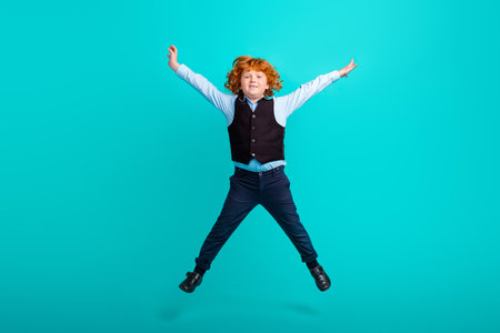 Full length photo of active energetic boy jumping raise hands make star figure isolated on teal color backgroundの写真素材