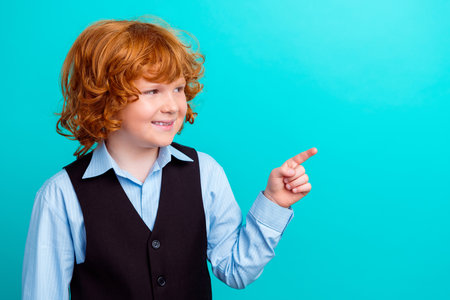 Photo portrait of adorable foxy wavy hair boy pointing look empty space wear trendy school outfit isolated on aquamarine color backgroundの写真素材