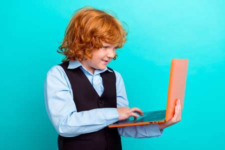 Photo portrait of adorable foxy wavy hair boy laptop little businessman wear trendy school outfit isolated on aquamarine color backgroundの写真素材