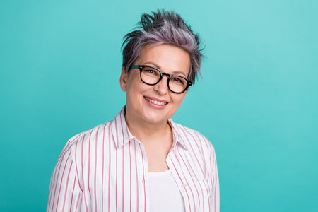 Portrait of attractive confident middle age woman smiling cheerful wear striped shirt eyeglasses isolated teal color backgroundの写真素材