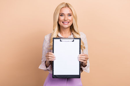 Photo of gorgeous positive lady boss ceo demonstrate signed contract successful deal isolated on beige color backgroundの写真素材