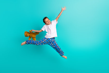 Full body portrait of carefree cheerful little person jump hold soft teddy bear toy empty space isolated on turquoise color backgroundの写真素材