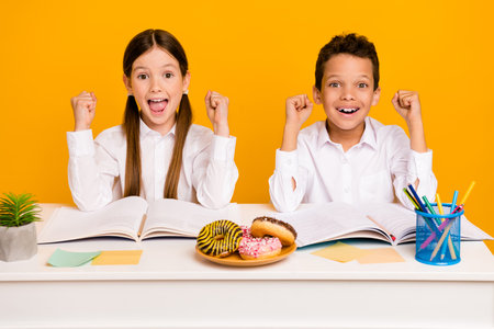 Photo of excited friends schoolkid girl boy raise fists up achieve a grades on test isolated vivid color backgroundの写真素材