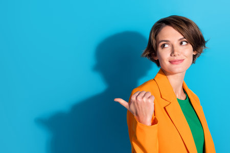 Portrait of young advertising manager bob brown hair woman direct finger mockup look interested good deal isolated on blue color backgroundの写真素材