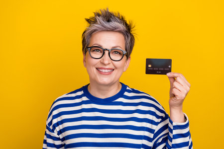 Portrait of attractive granny woman wear striped shirt demonstrating her non cash salary plastic...