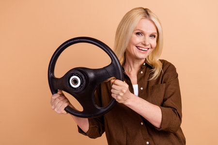 Photo cheerful lady young woman blonde hair car driver automobile high quality audio quattro technology isolated on beige color backgroundの写真素材