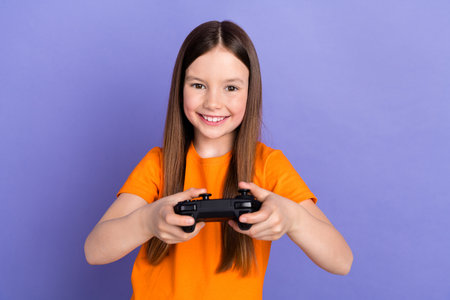 Portrait of satisfied schoolgirl with long hair wear stylish t-shirt hold joystick isolated on...