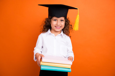 Photo of little pupil hold book for doing homework isolated on vivid color backgroundの写真素材