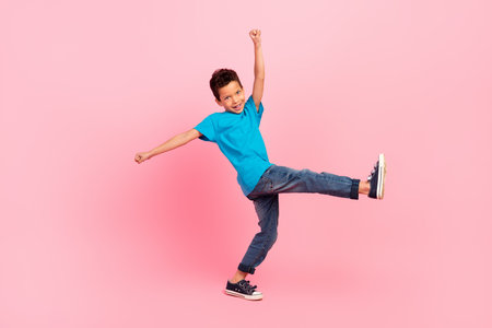 Full length photo of pretty excited little boy dressed blue t-shirt walking dancing isolated pink color backgroundの写真素材