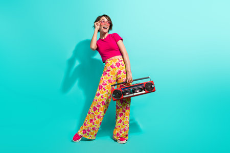 Full length photo of excited funky lady flower print pants enjoying boom box looking empty space...