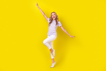 Full size photo of adorable girlish girl wear violet polo arms folded hold hands like wings flying isolated on yellow color backgroundの写真素材