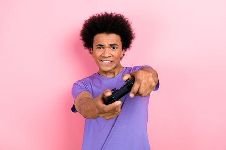 Portrait of focused funky guy with perming coiffure wear t-shirt hold playstation joystick biting...