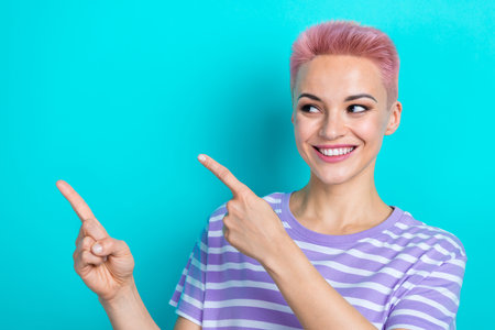 Photo of positive lovely lady beaming smile look indicate fingers empty space offer isolated on teal...