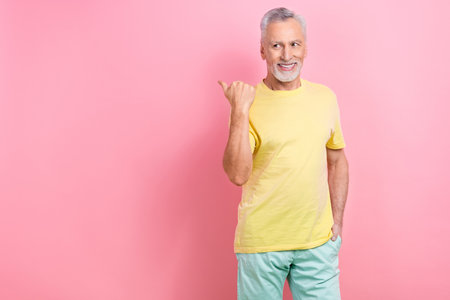 Photo of toothy beaming man with white gray beard dressed yellow t-shirt look directing empty space...
