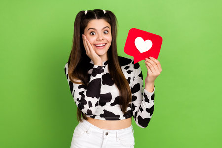 Photo of excited funky lady wear cow skin shirt arm cheek rising heart like card isolated green...