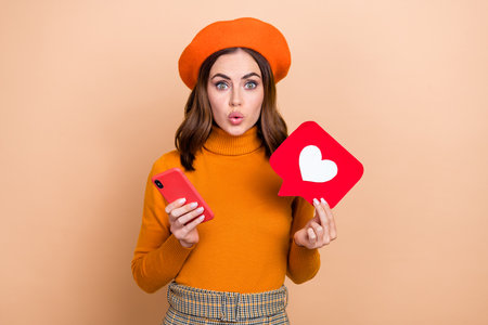 Photo of impressed pretty lady pouted lips hands hold telephone paper like card isolated on beige...