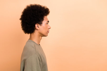 Side profile photo of good mood pleasant guy with afro hairstyle wear khaki shirt look empty space isolated on beige color backgroundの写真素材