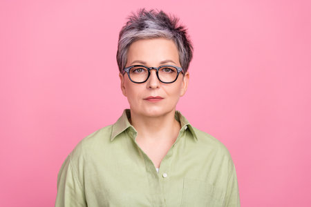 Portrait of focused intelligent corporate ceo lady calm concentrated face wear green shirt isolated on pink color backgroundの写真素材