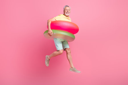 Full body photo of tourist active lifestyle swim abroad warm ocean water retired man wear double lifebuoys isolated on pink color backgroundの写真素材