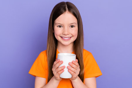 Portrait photo of optimistic little cute daughter kid childhood holding cup warm cacao tasty beverage isolated on violet color backgroundの写真素材