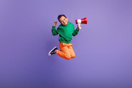 Photo of positive latin boy wear stylish pullover hold toa raise fist rejoice success isolated on purple color backgroundの写真素材