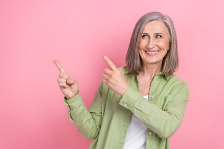 Photo of attractive marketing director old woman wear khaki stylish shirt direct fingers novelty message isolated on pink color backgroundの写真素材