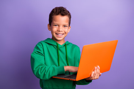 Photo of charming positive small boy wear green sweatshirt communicating modern device isolated violet color backgroundの写真素材