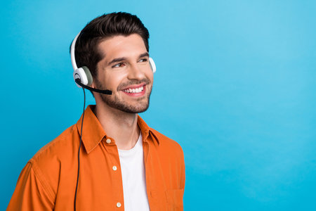 Portrait of positive cheerful person beaming smile communicate clients headset look empty space ad isolated on blue color backgroundの写真素材