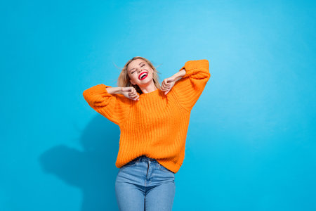 Portrait of nice satisfied girlish woman with bob hairstyle dressed knitwear sweater dancing having fun isolated on blue color backgroundの写真素材