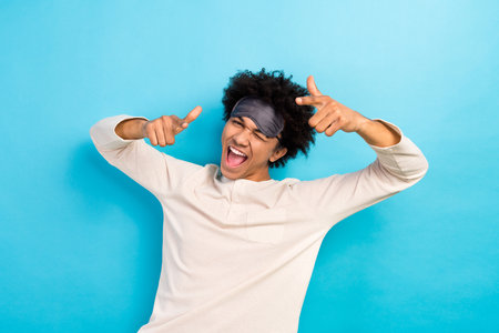 Photo portrait of attractive young man crazy dancing finger point you wear trendy white pajama clothes isolated on blue color backgroundの写真素材