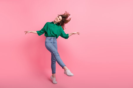 Full length photo of pretty cute lady wear green shirt having fun dancing empty space isolated pink color backgroundの写真素材
