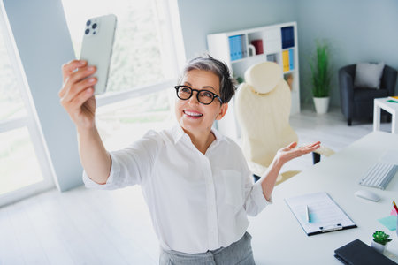 Photo of happy smiling lady boss dressed white shirt talking video call modern gadget indoors workstation workshopの写真素材