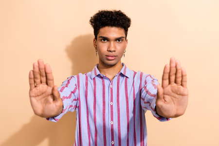 Portrait of serious confident guy with earrings dressed stylish shirt stretching arms stopping you...
