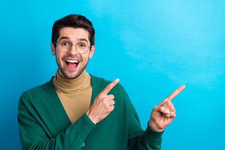 Photo of astonished corporate crazy person indicate fingers empty space offer ad isolated on blue color backgroundの写真素材