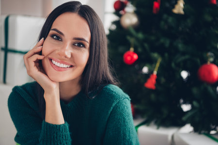 Photo of sweet good mood girl wear xmas green pullover arm cheek smiling indoors home roomの写真素材