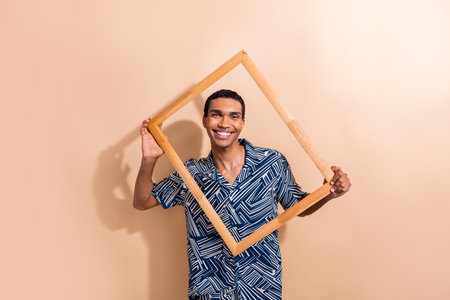 Photo portrait of attractive young man hold wooden frame photographing wear trendy blue print...