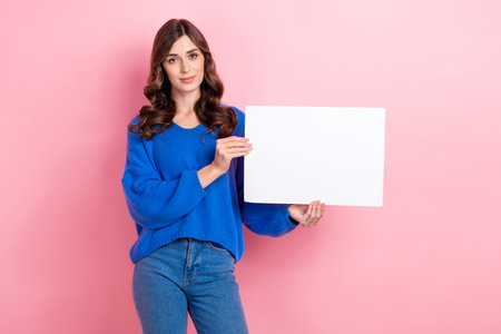 Photo portrait of pretty young girl hold paper sheet announce banner dressed stylish blue outfit isolated on pink color backgroundの写真素材